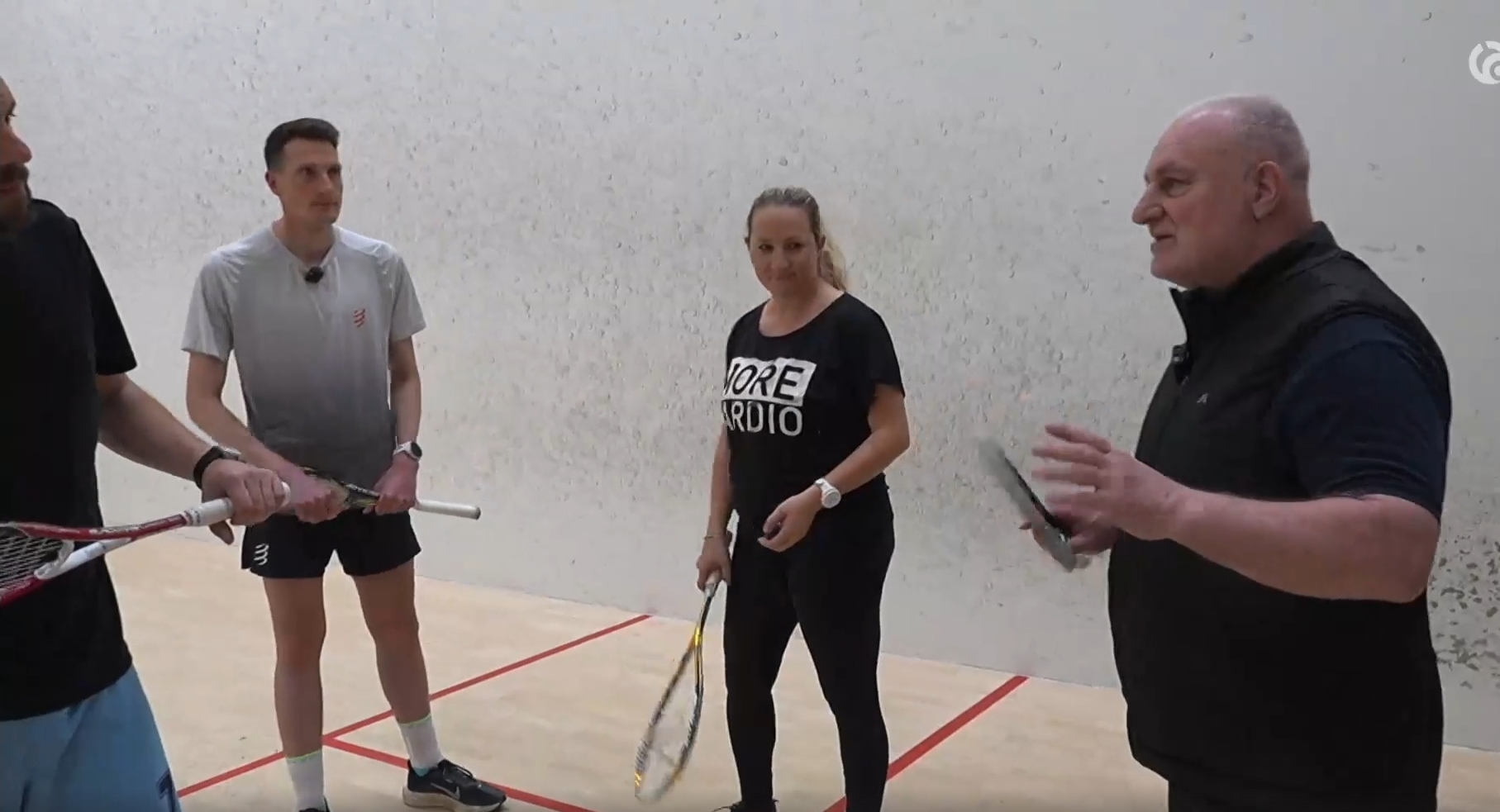 Alexandre Guenin donne des explications à des membres de la rédaction de Canal Alpha, raquette en main, sur un court de squash