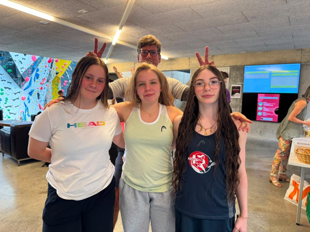 Trois joueuses juniors posent en riant, un coéquipier leur fait des oreilles de lapin