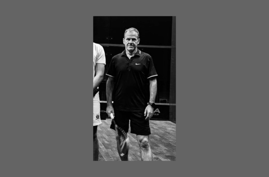 Portrait en noir et blanc de Lukas Gadola, raquette en main, sur un court de squash