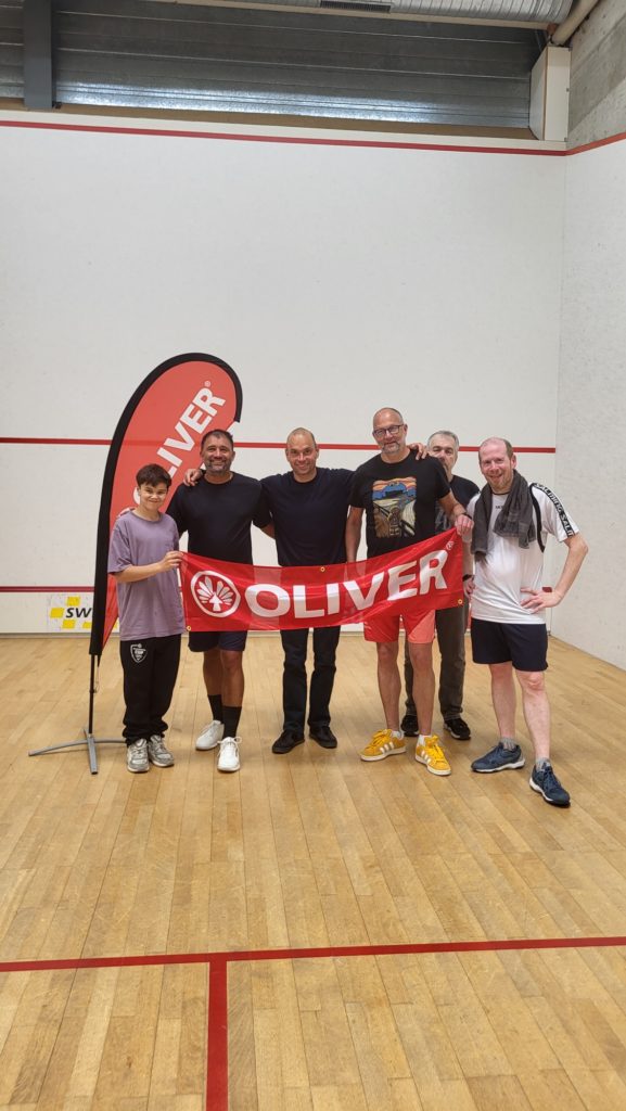 Six participants du SR Fun Tour 2025/26 tiennent une banderole Oliver sur un court de squash