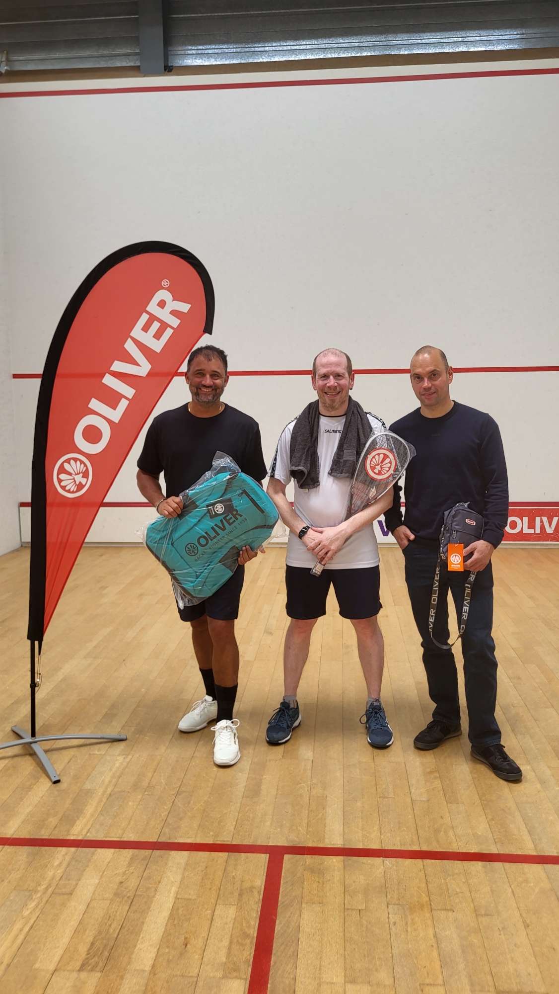 Les trois premiers du classement final du SR Fun Tour 2025/26 posent avec leurs prix Oliver sur un court de squash